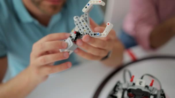 Крупный план инженера-мужчины, изучающего детали роботизированной руки — стоковое видео