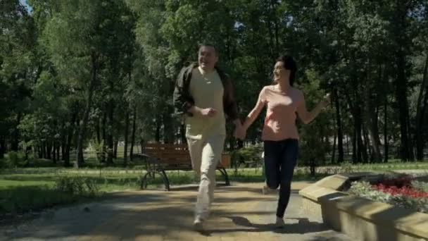 Радостная пара бегает по парку — стоковое видео