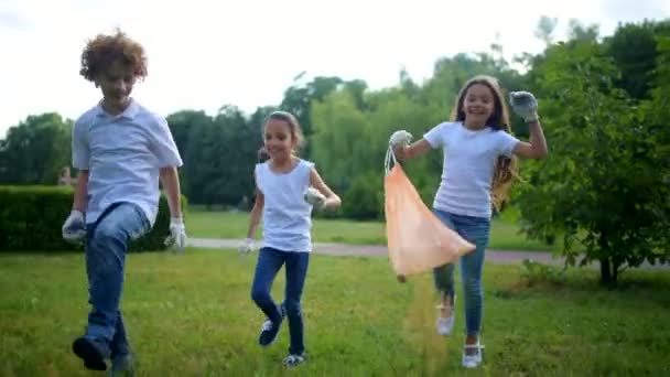 Очаровательные дети прыгают во время волонтерства и уборки на открытом воздухе — стоковое видео