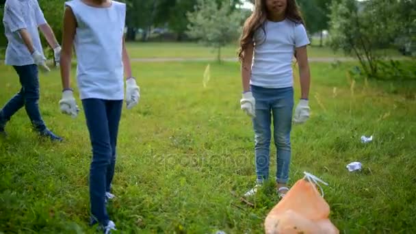 Уставшие, но внимательные маленькие добровольцы, соревнующиеся в уборке — стоковое видео