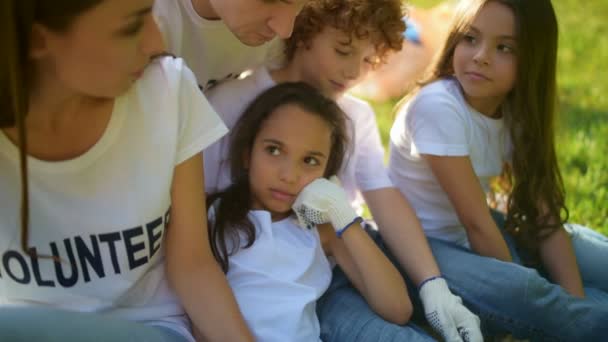 Close up van schattige peinzende kinderen rusten met vrijwilligers — Stockvideo