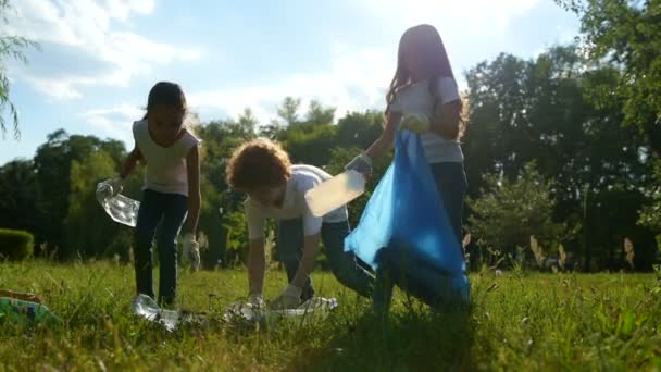 Pequeños ambientalistas inteligentes poniendo botellas de plástico en bolsas de basura — Vídeos de Stock