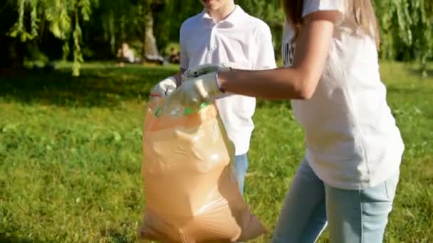 Niños cuidadosos ayudando a voluntarios con la clasificación de basura mientras limpian al aire libre — Vídeos de Stock