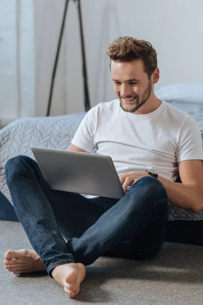 Homem encantador sorrindo enquanto trabalhava com computador — Fotografia de Stock