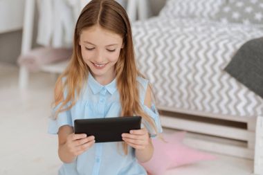Tablet bilgisayarda oynarken gülen sevimli küçük hanım