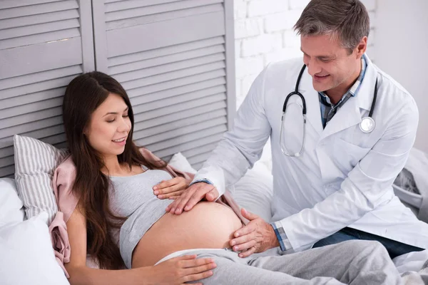 Positive delighted pregnant woman looking at her baby bump — Stock Photo, Image