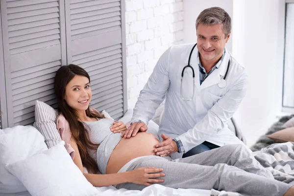 Médico sorridente fazendo massagem na barriga — Fotografia de Stock