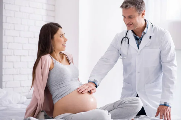 Delighted medical worker putting his hand on the baby bump — Stock Photo, Image