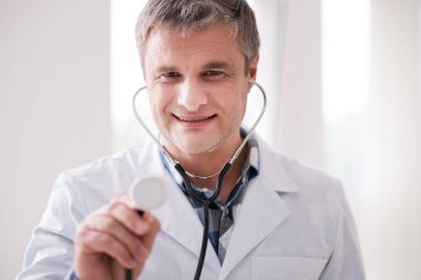 Şu anda stetoskop kullanarak doktor gülümseyen