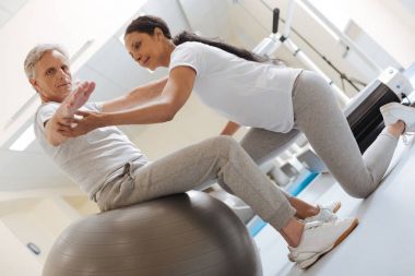 Fitness topu üzerinde oturan ciddi gri saçlı adam