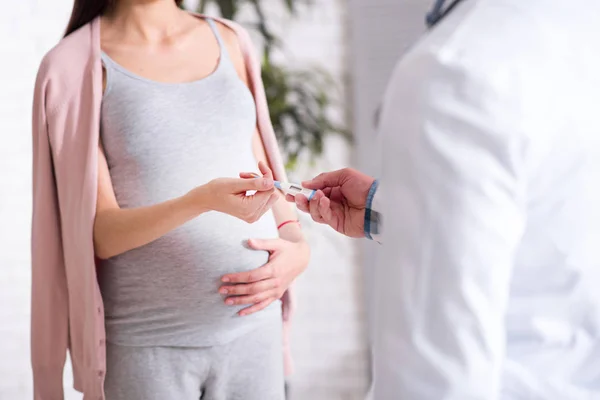 Acercamiento de la mujer embarazada que de pie frente a su médico — Foto de Stock