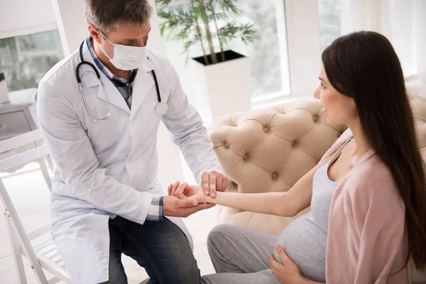 Serious doctor in mask looking at his patient — Stock Photo, Image