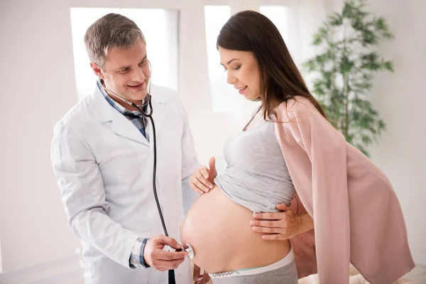 Raadselachtige zwangerschap aandachtig kijken naar haar buik — Stockfoto