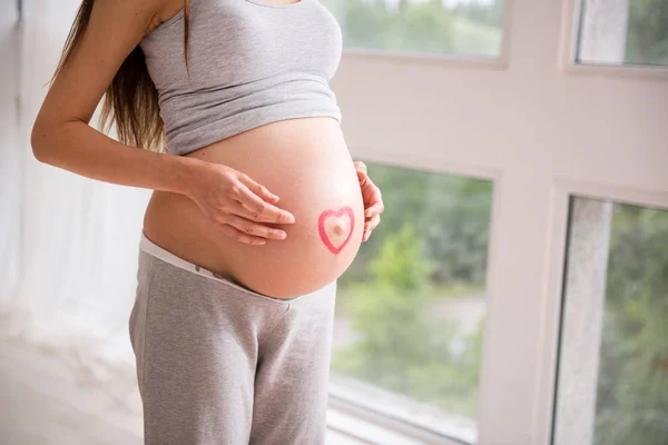 Zachwycony Kobieta w ciąży, pozowanie w pobliżu okna — Zdjęcie stockowe