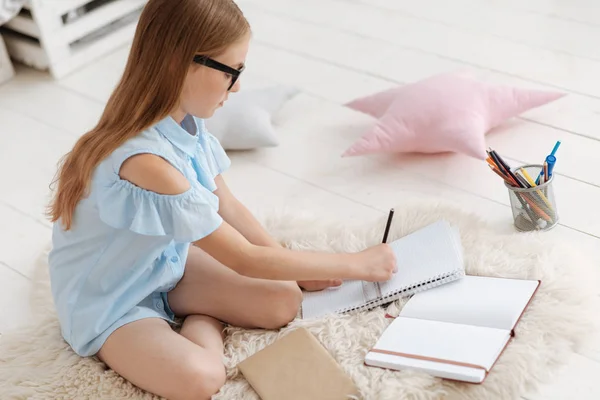 Allvarlig skolflicka med fokus på hem uppgift — Stockfoto