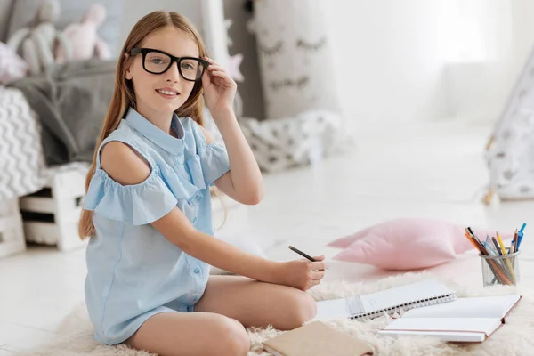 Smart young lady posing for camera while preparing school assignment — Stock Photo, Image
