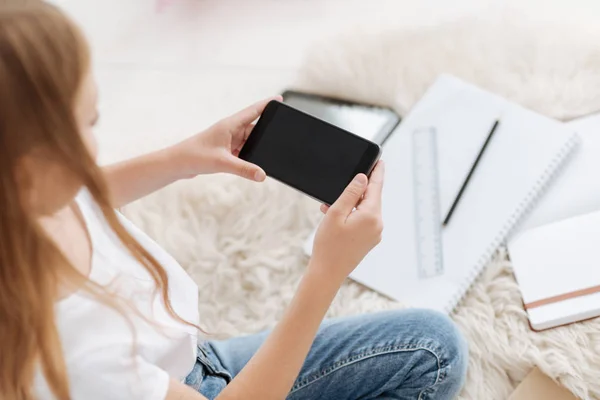 Junge Frau sitzt auf dem Boden und hält Smartphone — Stockfoto