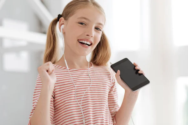 Beaming schoolgirl getting excited with music plying — Stock Photo, Image