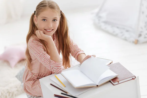 Bastante joven mujer sonriendo en la cámara mientras estudia — Foto de Stock