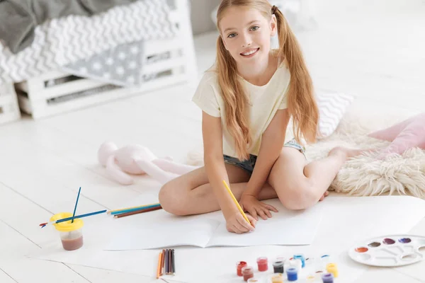 Beautiful girl looking into camera while drawing — Stock Photo, Image