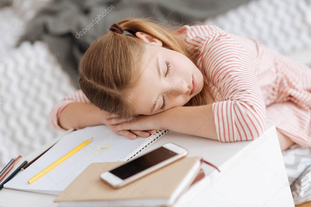Tired female youngster sleeping on table