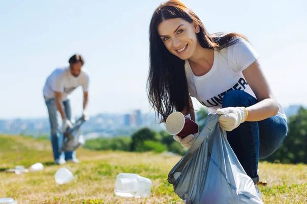 Мотивированная восхитительная женщина, убирающая мусор на лужайке. — стоковое фото