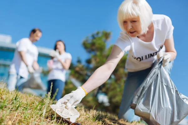 Aktiva år damen plocka upp skräp i parken — Stockfoto