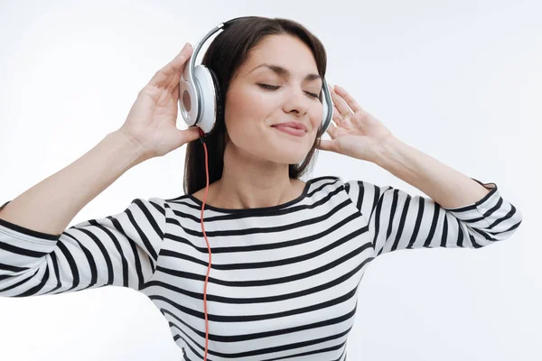 Pozitivní potěšen bruneta uvedení ruce na sluchátka — Stock fotografie