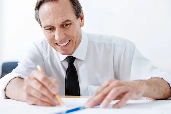 Pleasant man tracing lines on a blueprint — Stock Photo, Image