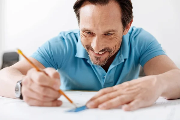 Усміхнений чоловік відстежує лінії з олівцем і лінійкою — стокове фото