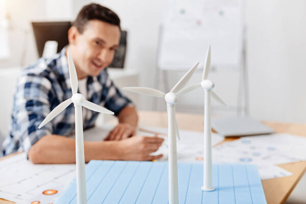 Улыбающийся человек копирует детали конструкции ветряных турбин
