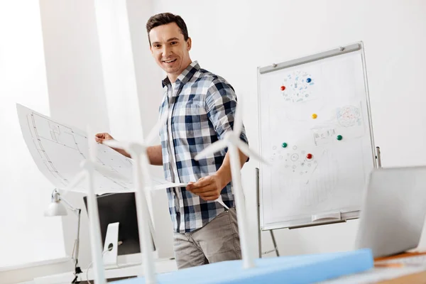 Architect comparing his blueprint with wind turbine model construction