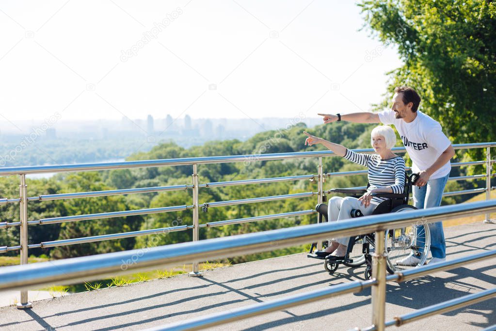Kind bright man taking disabled lady for a walk