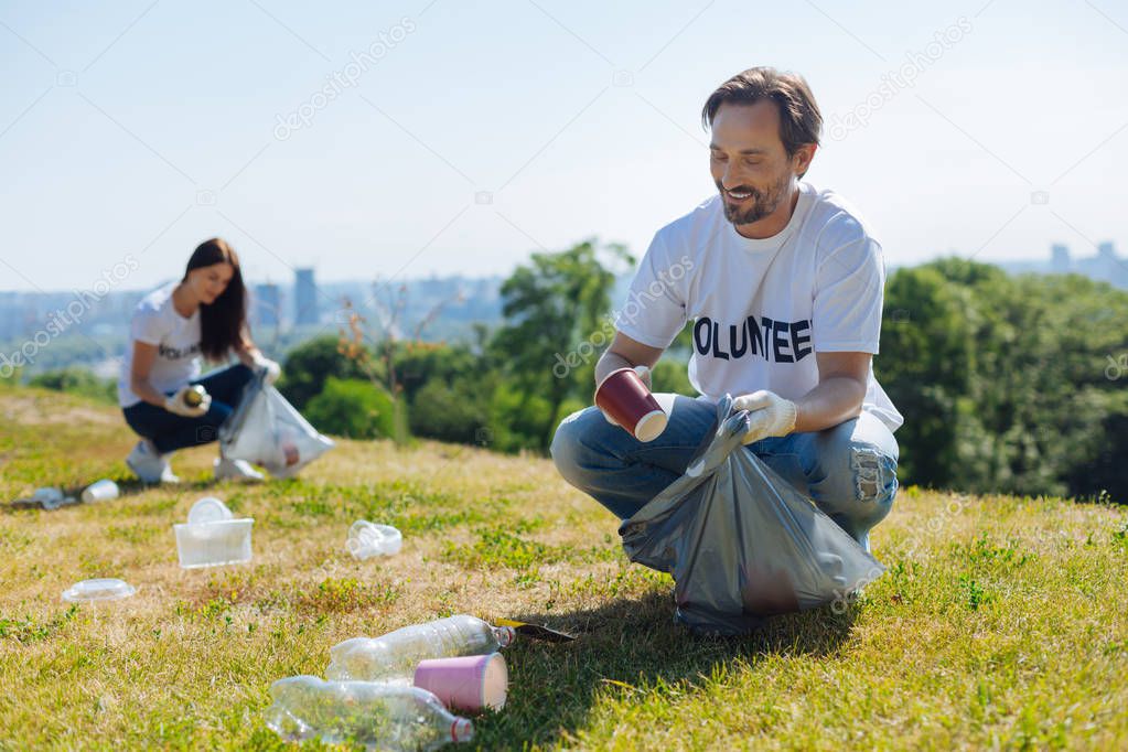 Focused motivated man cleaning local park from litter