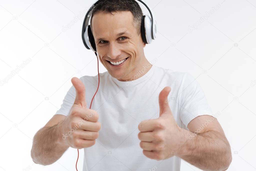 Positive delighted young man holding his thumbs up