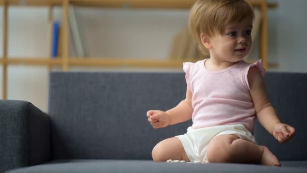Гарний маленький малюк сидить на дивані — стокове відео