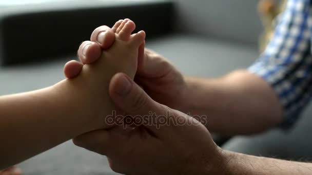 Caring father massaging a foot of her little baby — Stock Video