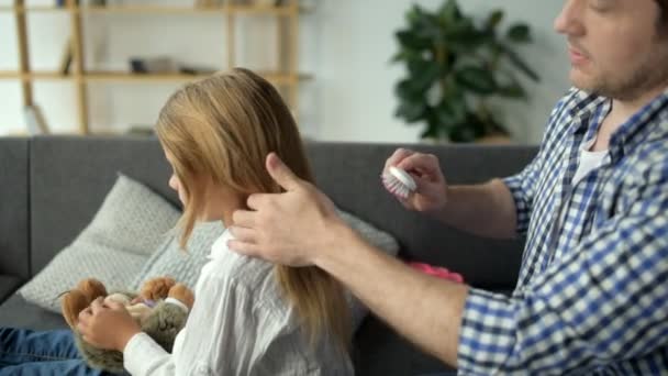 Позитивный отец, расчесывающий волосы своей милой дочери — стоковое видео