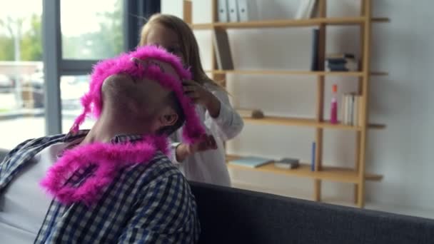 Joyful smiling girl wearing a pink scarf on her father — Stock Video