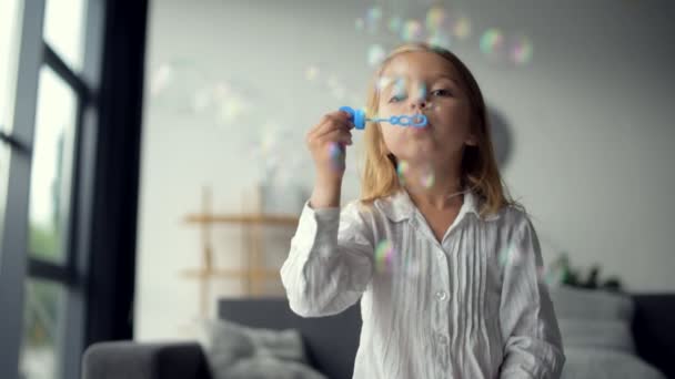 Niedliche positive kleines Mädchen pustet Seifenblasen — Stockvideo