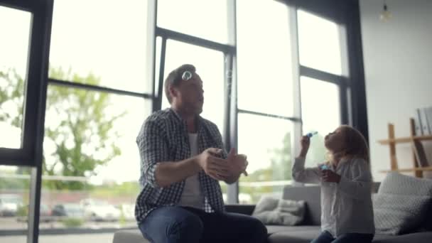 Cheerful loving father blowing soap bubbles with his daughter — Stock Video