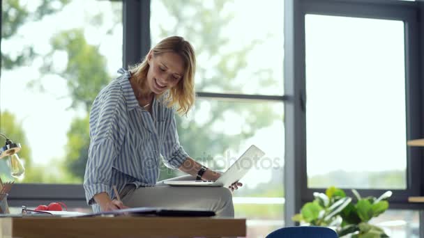 Joyful kvinnlig student sitter på bord samtidigt studera online — Stockvideo