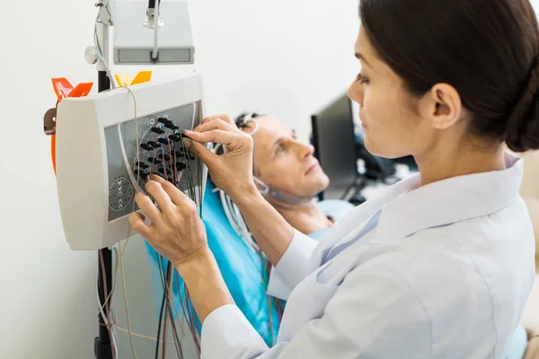 Médica sintonizando eletroencefalógrafo moderno — Fotografia de Stock