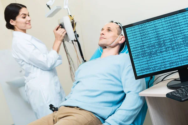 Hombre joven con sus ondas cerebrales registradas durante la electroencefalografía —  Fotos de Stock