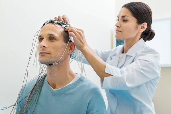 Médecin féminin mettant des électrodes sur la tête des patients — Photo
