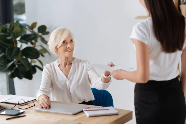 Nette freundliche Frau, die ihrer Sekretärin ein Dokument überreicht — Stockfoto