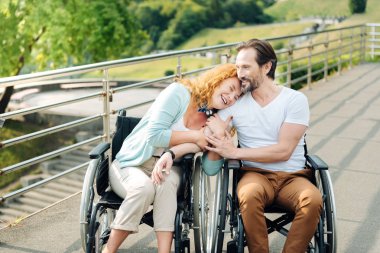 Sevgi dolu iskemleyi kocası kucaklayan neşeli kadın kıdemli