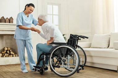 Neşeli yararlı caregiver hasta elini tutarak