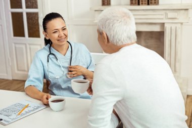 Onu hasta ile çay içiyor neşeli pozitif caregiver