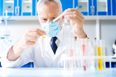 Kendine güvenen Uygulayıcı mavi sıvıyı tüpün içine ekleme